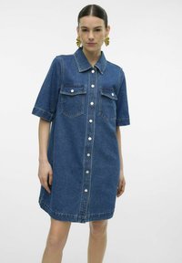 Denim skjortekjole, kort erm, lys blå vask, knappestolpe foran, to brystlommer, synlige sømdetaljer, avslappet passform.