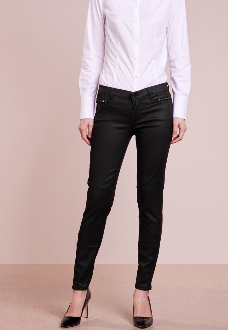 Svarta, slim-fit byxor med en slät textur, med dekorativa dragkedjor och panel sömnad. Kombinerade med en vit åtsittande skjorta och svarta klackar.