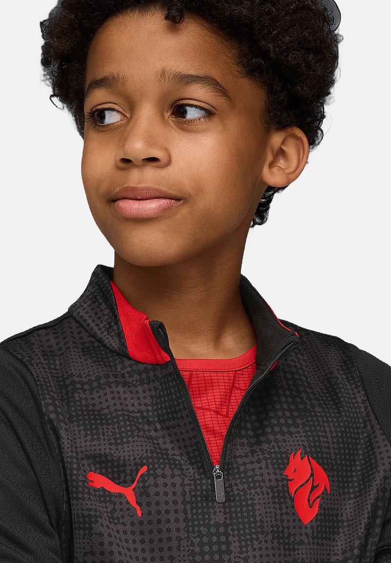 Schwarze Zip-Jacke mit roten Akzenten. Verfügt über ein strukturiertes Design, das Puma-Logo und ein Löwenemblem. Die innere Schicht hat ein rot gemustertes Hemd.