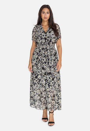 Vestido maxi negro con estampado floral, mangas cortas y fluidas, cintura elástica ajustada, y un print de flores blancas y amarillas sobre un fondo oscuro.