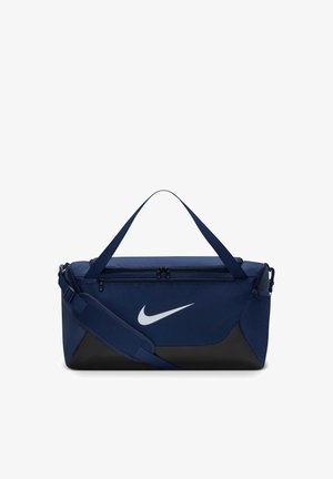 Sac de sport Nike bleu marine et noir avec deux compartiments à fermeture éclair, bandoulière réglable et poignées de transport sur fond blanc.