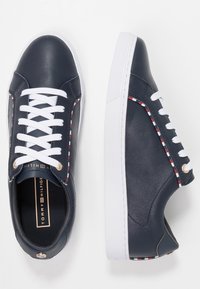 Sneakers in pelle blu navy con lacci bianchi, linguetta imbottita e suola in gomma bianca. Presentano cuciture decorative rosse e bianche lungo i lati.
