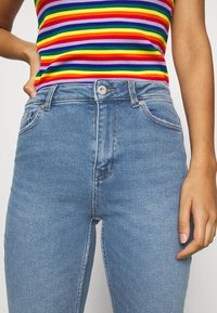 Ljust blå denim jeans med hög midja och slim fit, med knappknäppning fram, bältloops och subtil blekning på tyget.