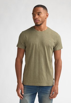 T-shirt manches courtes couleur vert olive en tissu doux avec un col rond, arborant un petit logo sur la poitrine et une coupe décontractée.