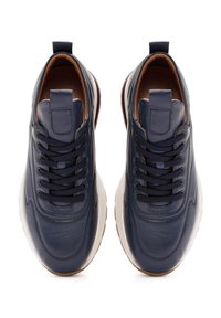 Een paar marineblauwe leren sneakers met zwarte veters en witte zolen, vanuit bovenaf gezien op een witte achtergrond.