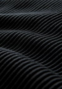 Tessuto nero con un motivo testurizzato a righe, che mette in risalto linee morbide e sottili variazioni di tonalità sulla superficie.