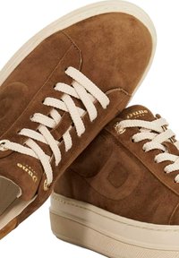 Brown suede sneakers with cream laces, gold eyelets, and a white rubber sole. Features a subtle logo and textured side panel detailing.