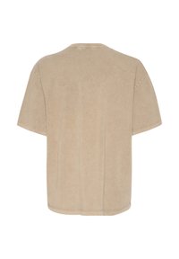 T-shirt beige surdimensionné avec un col rond, des manches courtes et une finition douce et texturée ; design minimaliste sans motifs ni logos visibles.