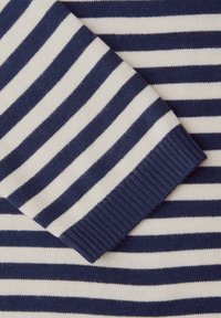 Tissu en tricot à rayures horizontales bleu marine et blanc avec un poignet côtelé replié, montrant le détail de la manche.