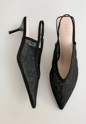 Fekete csipkeborítású slingback magassarkúk, hegyes orral és vékony stiletto sarkakkal. Virágmintás csipkeborítás és párnázott rózsaszín talpbetét a kényelem érdekében.