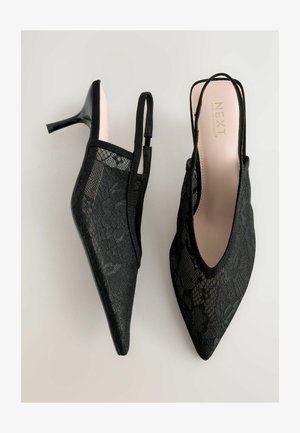 Sorte blonde slingback hæle med spidse tåer og slanke stiletto hæle. Har blomstret blonde mønster og polstrede pink indlægssåler for komfort.