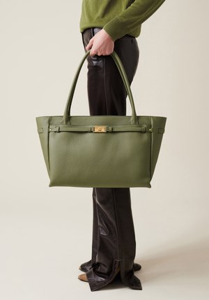 Sac fourre-tout en cuir vert avec finition texturée, deux longues poignées et un accent en métal doré sur le devant. Forme avec une silhouette structurée.