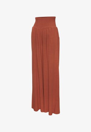 Long rust-colored skirt with a wide smocked waistband and flowing pleated fabric extending to the floor.