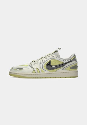 Nike sneaker in light gray and yellow. Features textured material, a prominent black swoosh, and mesh accents. Low-top design with laces.