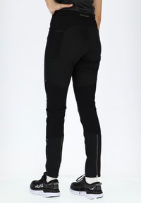 Black athletic pants made from stretchy material, featuring zippered pockets, a high waistband, and textured panels for added detail.