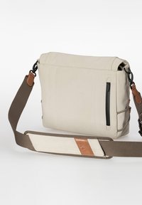 Beige schoudertas van stof met een voorvak met rits, een verstelbare bruine riem en leren accenten op de riem en het lichaam.