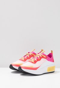 Pink and white sneakers with a mesh upper, yellow accents, rubber sole, and contrasting laces. Features a cushioned heel for comfort.