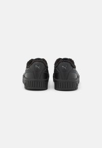 Baskets noires avec un col texturé et duveteux et un corps en cuir lisse. Caractéristiques : une semelle rainurée et un logo à l'arrière près du col.