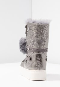 Botte argentée métallique mi-mollet avec broderies florales, bordure en fausse fourrure grise et pompons, lacets gris, fermeture éclair sur le côté et semelle en caoutchouc épaisse blanche.