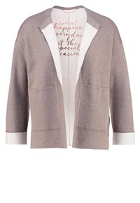 Béžový kardigán s volným střihem, otevřeným předním dílem, dvěma předními kapsami a kontrastními bílými rukávy. Obsahuje potištěnou vnitřní podšívku.