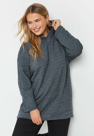 Harmaat pehmeät oversized-hupparit, joissa on pitkät hihat ja rento istuvuus, esitellään etutaskun ja sivuaukkojen kanssa helmaosassa.