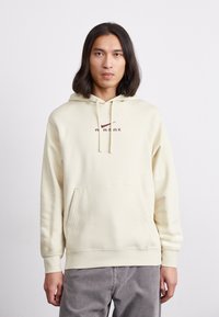 Krämsfärgad hooded sweatshirt med en framficka, som har en vinröd logotekst "AIR MAX" på bröstet. Mjuk tyg och vanlig passform.