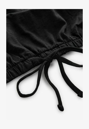 Svart tyg med en rynkad elastisk rem och dragsnören. Texturen verkar mjuk, med en slät yta och inga synliga mönster eller metallföremål.