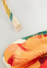 Sangle en tissu colorée avec crochet réglable doré et textile aux motifs vibrants orange, rouge et vert.