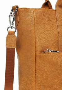 Béžová kožená kabelka s texturovaným povrchem, vybavená kapsou na zip a stříbrnými kovovými detaily. Součástí je nastavitelný popruh.