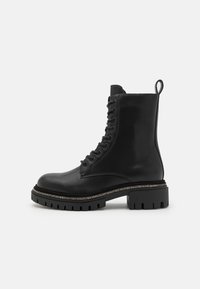 Black leather lace-up ankle boot with a rounded toe, thick chunky sole, and textured decorative stitching around the sole's edge.