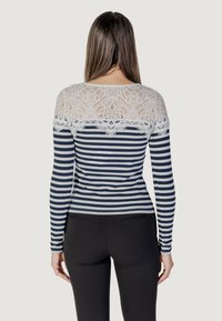 Maglietta a maniche lunghe con righe blu navy e bianche, con un'inserto in pizzo sul retro che crea un contrasto testurizzato. Vestibilità slim.