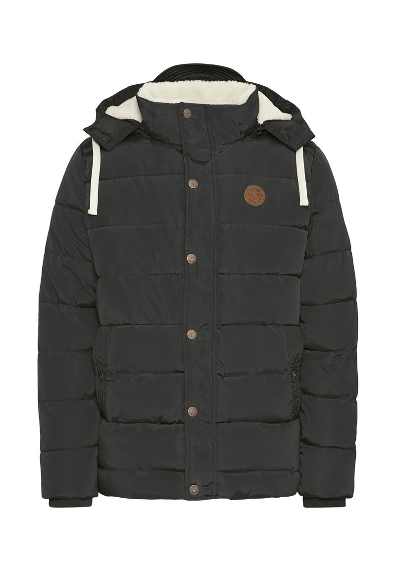 Veste noire rembourrée avec capuche doublée en fausse fourrure, fermetures à boutons-pression, poches latérales et un écusson circulaire marron sur la poitrine.