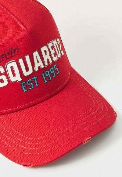 Röd basebollkeps med broderad "Canada" och "SQUARED2 EST 1995" i vitt och blått. Har en böjd skärm och sydda detaljer.