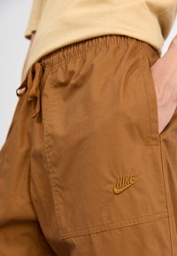 Barna Nike rövidnadrág, könnyű anyagból készült, rugalmas derékkal, zsinórral, oldalt egy kis hímzett logóval.