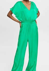 Mono verde satinado con escote en V, mangas cortas, cintura elástica y piernas anchas. Textura suave, diseño minimalista y color sólido.