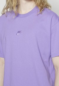 Paarse katoenen T-shirt met een ronde hals en korte mouwen, voorzien van een geborduurd Nike-logo op de borst. Zachte textuur, casual pasvorm.
