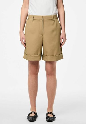 Shorts khaki au design ajusté, avec un ourlet retourné, des poches latérales et une texture lisse. Associés à des chaussures plates noires.