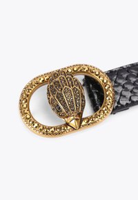 Ceinture en cuir noir avec une boucle ornée en forme d'oiseau en ton or, ornée de strass noirs et transparents, le tout dans un cadre décoratif ovale.