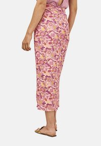 Falda midi floral en tonos rosa y amarillo, hecha de tejido ligero, con una cintura alta y una sutil abertura en la parte posterior.