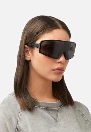 Melni lielizmēra saulesbrilles ar ģeometrisku rāmīti un tumšām lēcām, matēta apdare un izturīgas melnas kājiņas.