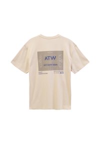 Beige bomulds T-shirt med grafisk print på ryggen med "ATW," "OFF DUTY GEAR," og tekniske detaljer i blå og grå.