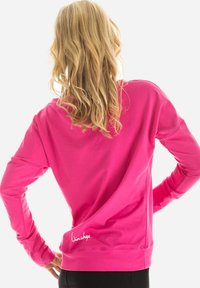 Fuchsia long-sleeve top met een ontspannen pasvorm, ronde hals en zachte textuur. Bevat geborduurd logo aan de onderste linkerzijde.
