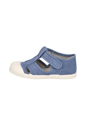 Sandalia para niño pequeño de lona azul con puntera de goma blanca, correa de velcro y lados recortados sobre fondo blanco.