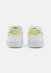 Baskets blanches avec des accents pastel vert doux, une surface texturée, un système de laçage et un logo au talon. Conception en double matériau.