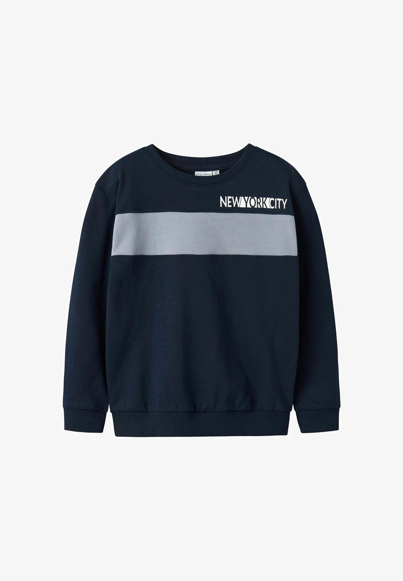 Svetilka v mornarsko modri barvi z sivo horizontalno črto. Ima napis "NEW YORK CITY" v beli barvi, okroglo ovratnik in rebrasto manšeto.