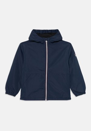 Veste marine en matériau léger et résistant à l'eau. Dotée d'une fermeture éclair à l'avant, de poignets élastiques et d'une capuche. Design simple sans motifs.