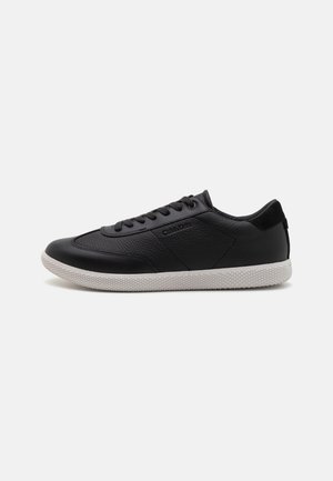 Black leather sneakers with a textured finish, featuring a white rubber sole, round toe, and flat laces. Logo on the side.
