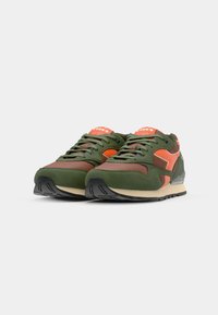 Green and brown athletic sneakers with orange accents, suede and mesh materials, padded tongue, textured rubber sole, and lace-up design.