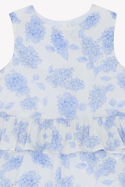 Blå blomstret kjole med hvit bakgrunn, volangkant og uten ermer, med lyseblå hortensia mønstre og blader.
