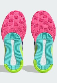 Schuhsohlen mit einer rosa strukturierten Oberfläche, hexagonalen Mustern, blauen Akzenten und einer weißen Zwischensohle mit grünen Details.